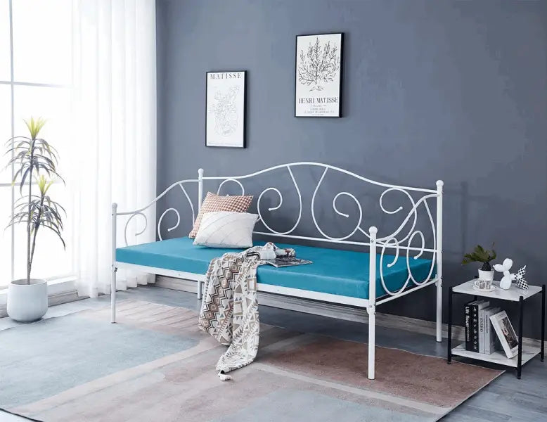 White metal daybed with turquoise cushioning and decorative scrollwork