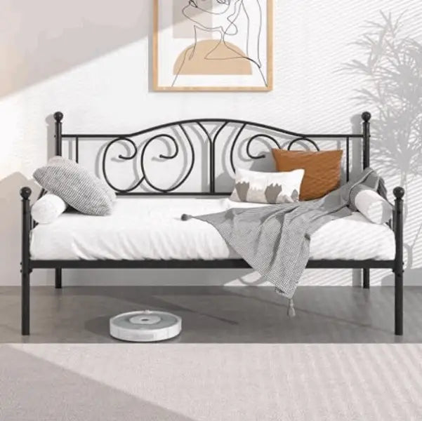 Black metal daybed with scrollwork design and white bedding