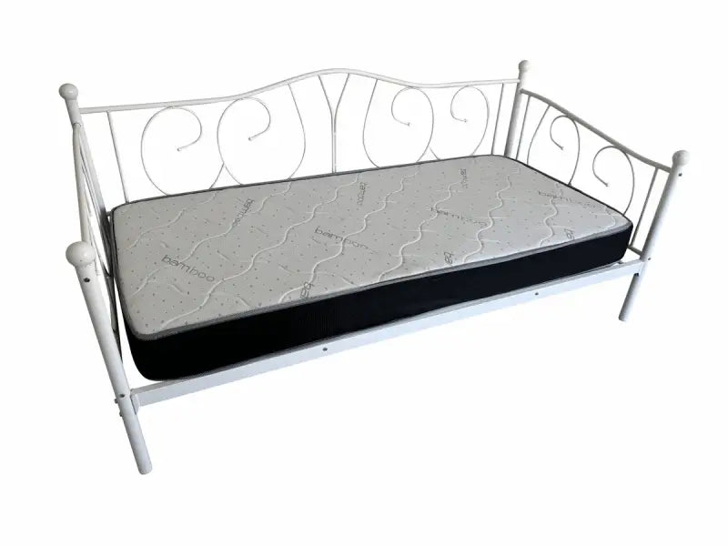 White metal daybed with scrollwork design and a dark mattress