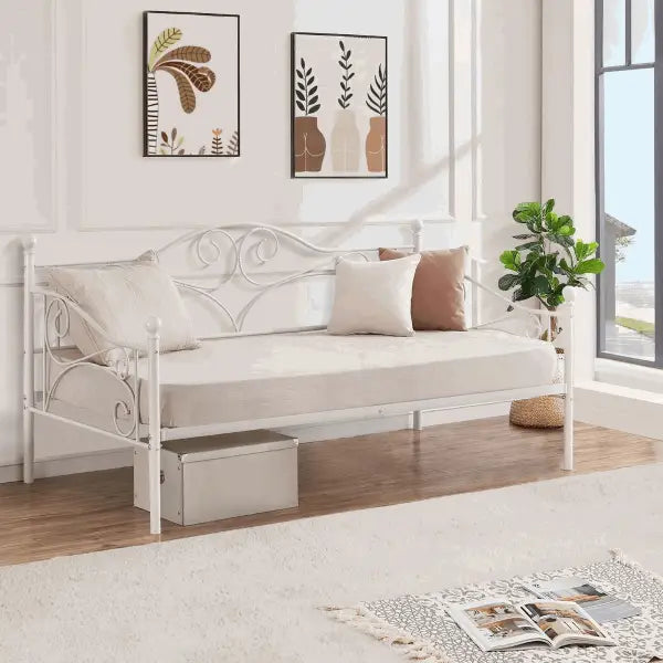 White metal daybed with decorative scrollwork and cushions